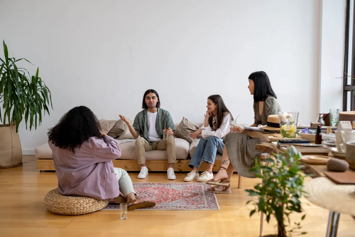 Four people sitting together and talking in a living room.
